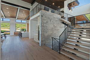 Staircase featuring wood ceiling, a high ceiling, plenty of natural light, wood finished floors, and recessed lighting