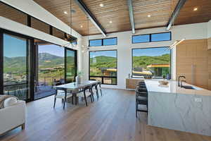 Dining space featuring a wood ceiling with exposed beams, a mountain view, light wood finished floors, recessed lighting, and a chandelier