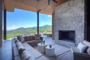 View of patio featuring a mountain view, an outdoor living space with a fireplace, and ceiling fan