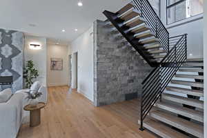 Staircase with wood finished floors and recessed lighting