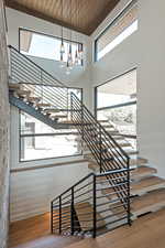 Staircase with a towering ceiling, wood finished floors, wooden ceiling, and a chandelier