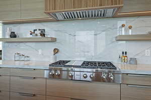Kitchen featuring ventilation hood, stainless steel gas cooktop, tasteful backsplash, and light stone counters