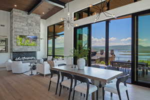 Dining space featuring a wooden ceiling with exposed beams, a chandelier, wood finished floors, a high ceiling, and a stone fireplace