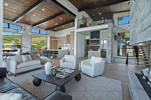 Living room with a wooden ceiling with exposed beams, a towering ceiling, a chandelier, stairs, and wood finished floors