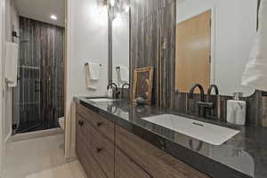 Bathroom featuring a shower stall, double vanity, recessed lighting, and tile patterned flooring