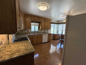 Kitchen with white appliances, a ceiling fan, tasteful backsplash, and dark wood-type flooring