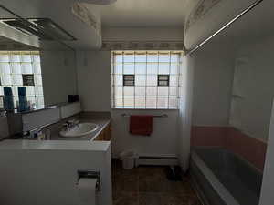 Full bath with a baseboard heating unit, tile patterned floors, vanity, and tub / shower combination