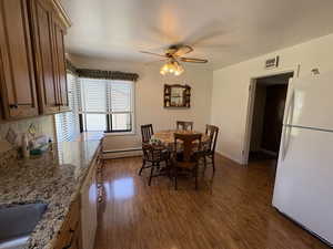 Dining area featuring a ceiling fan, dark wood-style flooring, and a baseboard heating unit
