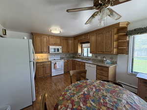 Kitchen featuring white appliances, a baseboard radiator, brown cabinets, open shelves, and a ceiling fan