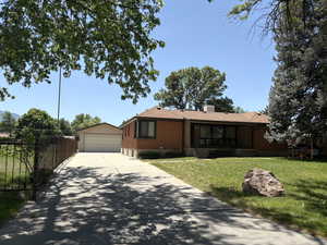 Ranch-style house featuring brick siding, a garage, an outdoor structure, and a chimney