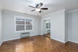 Unfurnished room featuring radiator heating unit, a ceiling fan, and crown molding