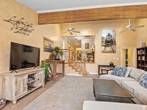 Living area with a ceiling fan, ornamental molding, stairway, and tile patterned flooring