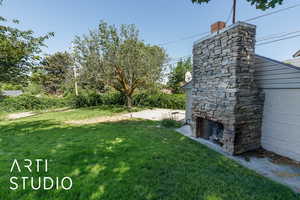 View of grassy yard with an outdoor stone fireplace