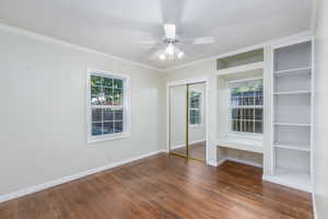 Unfurnished bedroom with wood finished floors, ornamental molding, and ceiling fan