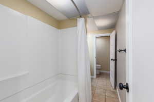 Full bathroom featuring shower / bath combo with shower curtain and tile patterned floors