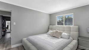 Bedroom with wood finished floors, ornamental molding, and a textured ceiling