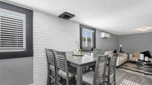 Dining space featuring a wall mounted AC, a textured ceiling, and wood finished floors