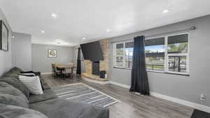 Living area featuring a textured ceiling, wood finished floors, recessed lighting, and a brick fireplace