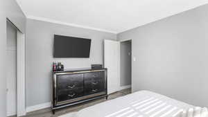 Bedroom featuring crown molding, wood finished floors, and a textured ceiling