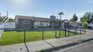 Ranch-style home with driveway, a fenced front yard, and a chimney