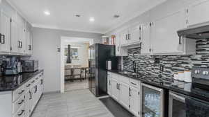 Kitchen featuring stainless steel appliances, beverage cooler, tasteful backsplash, crown molding, and recessed lighting