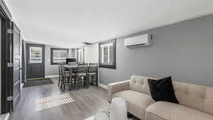 Living room featuring a wall unit AC, a textured ceiling, and wood finished floors