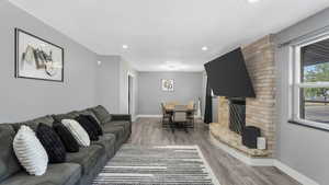 Living room featuring light wood-style flooring, a textured ceiling, recessed lighting, and a brick fireplace