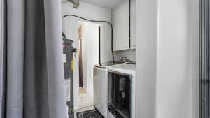 Laundry room with cabinet space, washer and clothes dryer, gas water heater, and tile patterned flooring