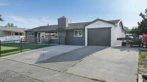 Ranch-style house featuring concrete driveway, an attached garage, a chimney, and a shingled roof