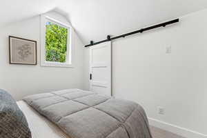 Bedroom featuring a barn door, carpet floors, and lofted ceiling
