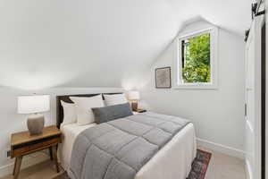 Carpeted bedroom featuring vaulted ceiling and baseboards