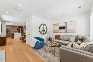 Living room with light wood-type flooring, recessed lighting, and brick wall
