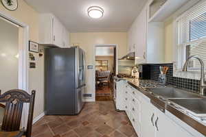Kitchen featuring stainless steel appliances, plenty of natural light, white cabinets, and under cabinet range hood