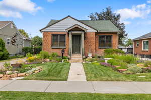 Bungalow-style home with brick siding, a front lawn, and a shingled roof