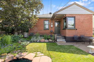 View of front of house featuring brick siding, a front yard, and a patio area