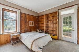 Carpeted bedroom featuring ornamental molding, access to outside, and wood walls