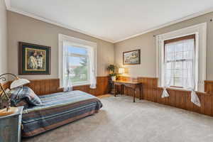 Bedroom with wainscoting, multiple windows, wood walls, carpet, and ornamental molding