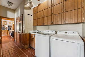 Laundry room with cabinet space, washer and dryer, dark tile patterned floors, and electric panel