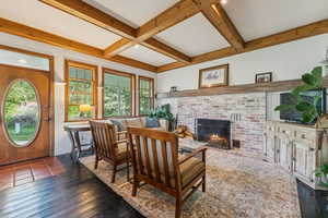 Living room featuring a fireplace, beamed ceiling, coffered ceiling, and dark wood finished floors