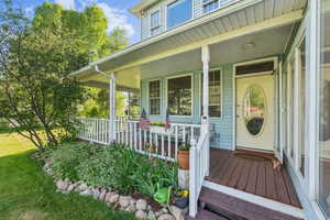View of exterior entry featuring covered porch and a lawn