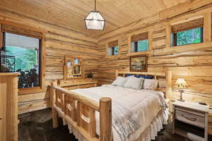 Bedroom featuring dark carpet, wood ceiling, and rustic walls