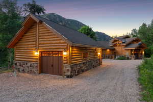 Log home with stone siding, log exterior, a mountain view, roof with shingles, and driveway