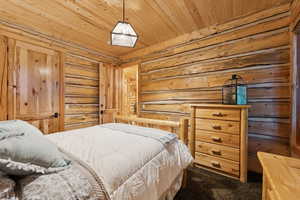 Bedroom featuring dark colored carpet and wooden ceiling