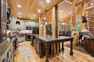 Kitchen with black microwave, refrigerator, light wood-style flooring, a kitchen bar, and a large island