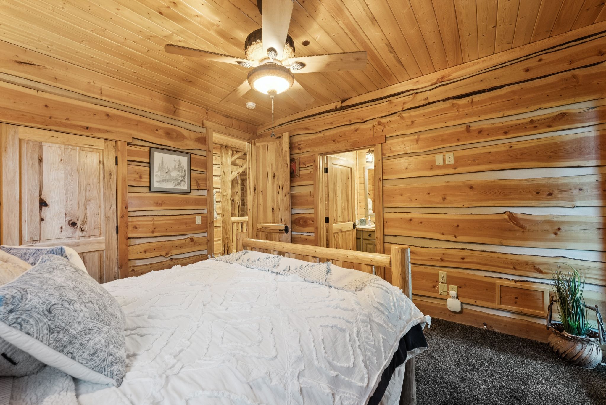 Carpeted bedroom with wood walls, tongue-in-groove ceiling, and ceiling fan