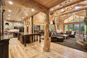 Living room with high vaulted ceiling, light wood finished floors, recessed lighting, a wooden ceiling with exposed beams, and beverage cooler