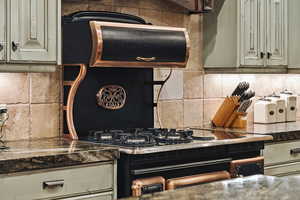 Kitchen with cream cabinets, tasteful backsplash, and dark countertops