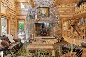 Living room with log walls, a wood stove, a wooden ceiling with exposed beams, and a high ceiling