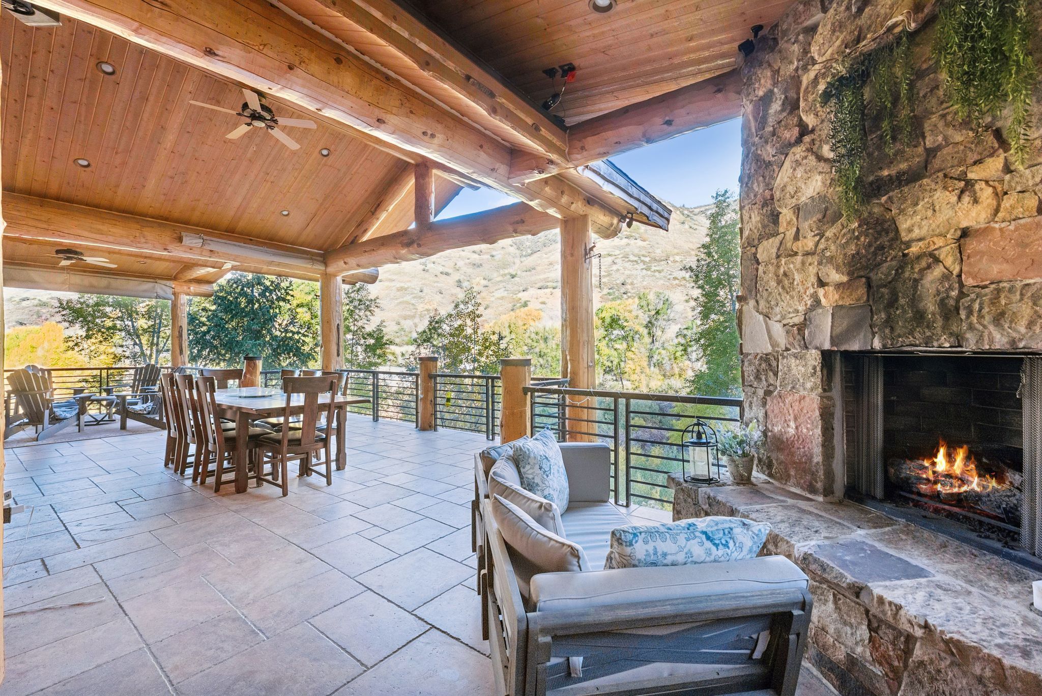View of patio / terrace with ceiling fan, outdoor dining area, an outdoor stone fireplace, and a mountain view