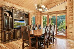Dining room featuring wood ceiling, light wood-type flooring, healthy amount of natural light, a chandelier, and vaulted ceiling